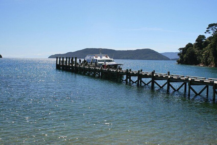 A wooden pier extending into calm waters, a boat docked at the end, and a hilly landscape in the background. 1
