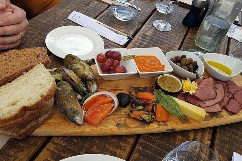 A wooden board with various foods including bread, cheese, olives, and meats. 3