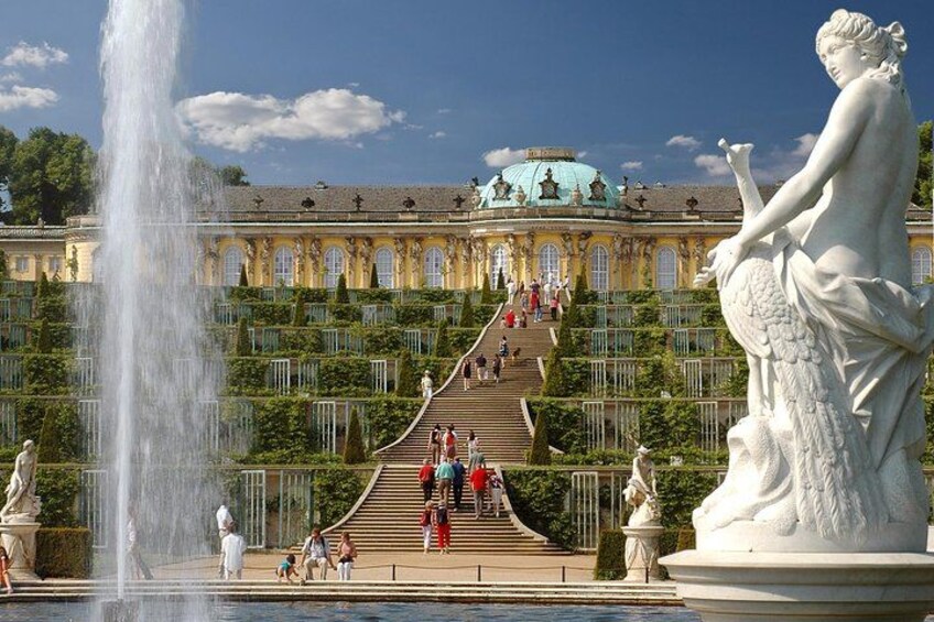 A grand palace with a fountain, a statue, and a staircase leading to the entrance. 3