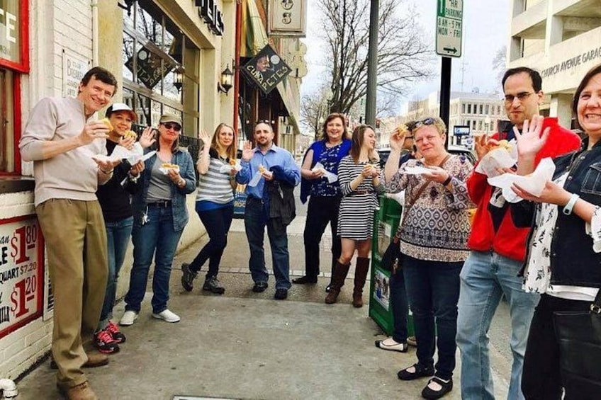 Un groupe de personnes se tient sur un trottoir, certaines tenant des aliments. 1