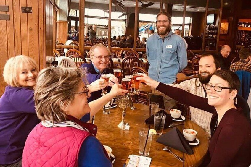 A group of people toasting with drinks at a wooden table in a restaurant. 2