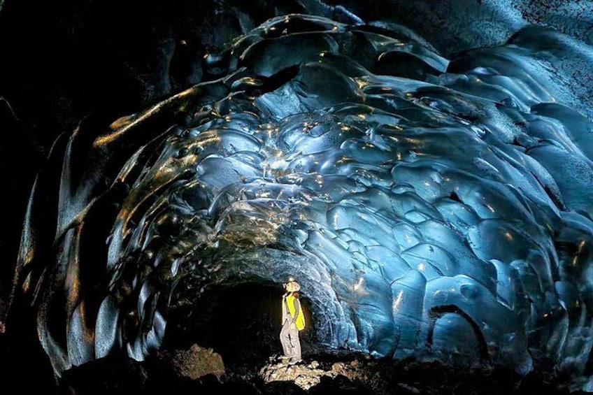 Una persona de pie en una cueva con formaciones de hielo. 5