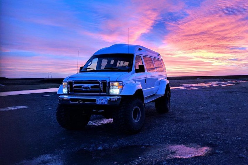 Una camioneta blanca estacionada en una carretera con un cielo al atardecer de fondo. 3