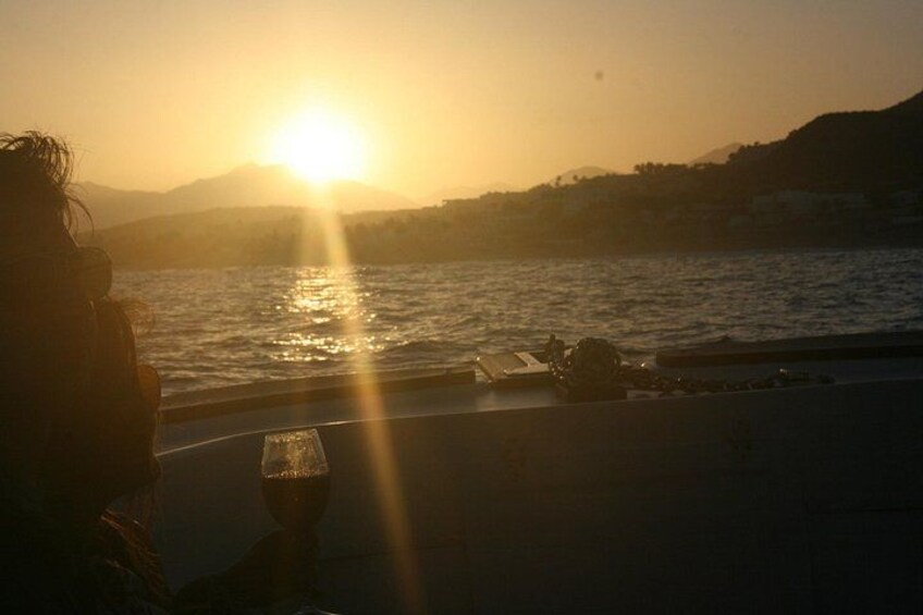 A sunset over a body of water with a silhouette of a person and a glass on a table. 5
