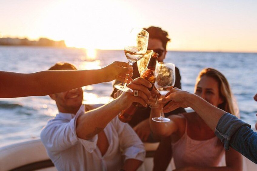 People toasting with champagne glasses on a boat at sunset. 1