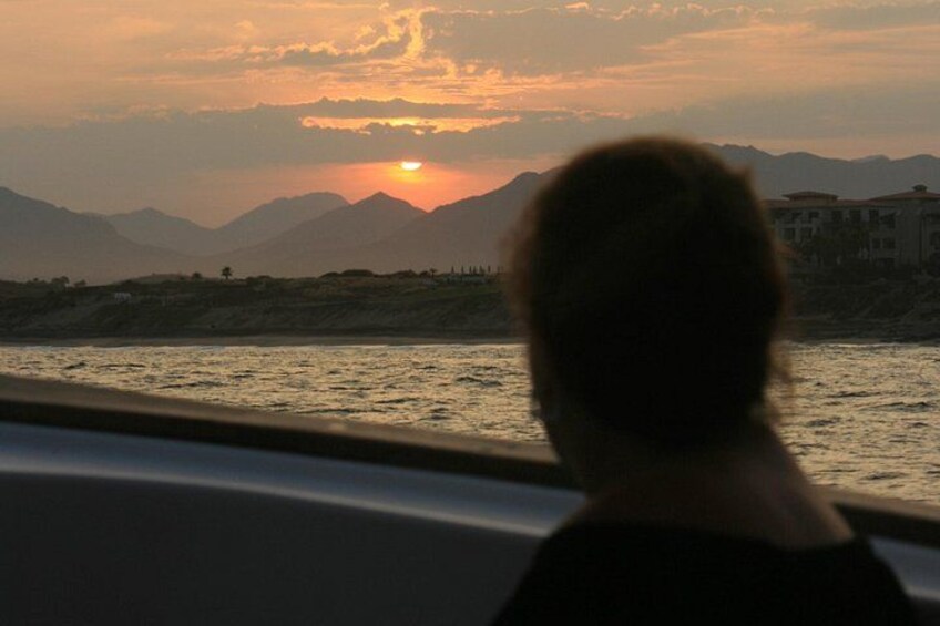 A sunset over mountains with a silhouette of a person in the foreground. 2
