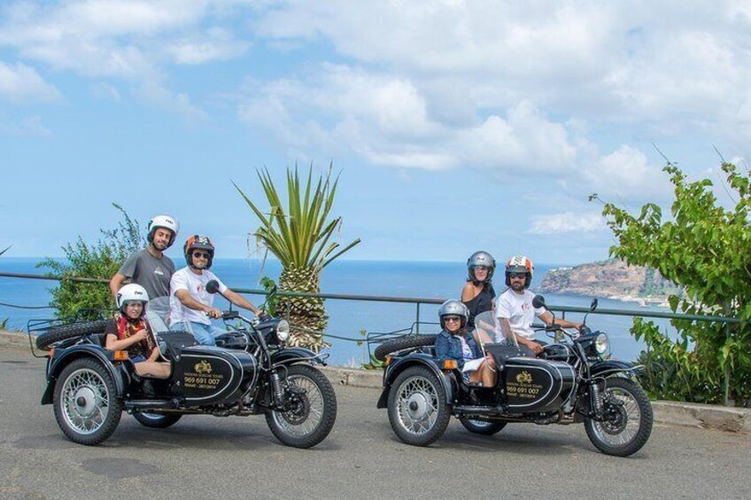 A group of people on a motorcycle tour with a scenic coastal backdrop. 5