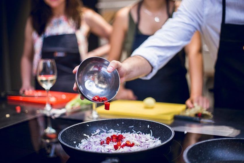 Una persona prepara cibo, tagliando cipolle rosse e peperoni rossi in una cucina. 2