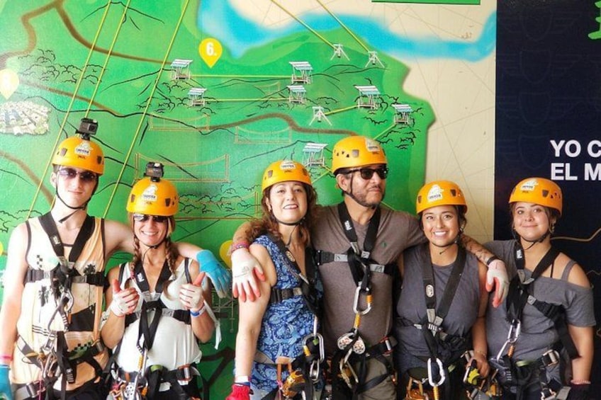 A group of people wearing helmets and harnesses, standing in front of a map with solar panels and a green landscape. 3