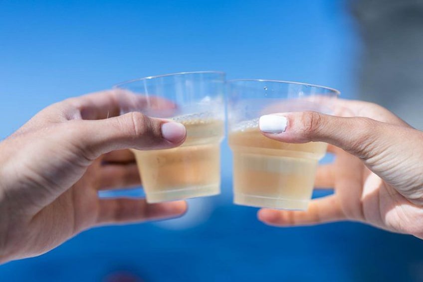 Två händer håller i genomskinliga glas med en ljusfärgad dryck i. 4
