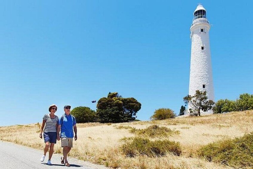 A lighthouse, a couple walking on a path, and dry grassland. 4