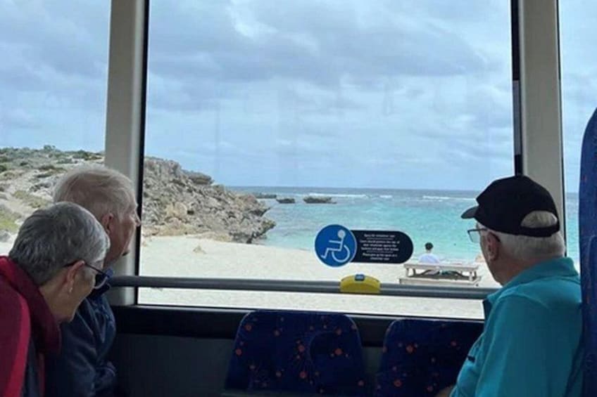 En grupp människor står och tittar ut genom ett fönster på en strand, och en skylt visar att stranden är tillgänglig för rullstolsburna. 5