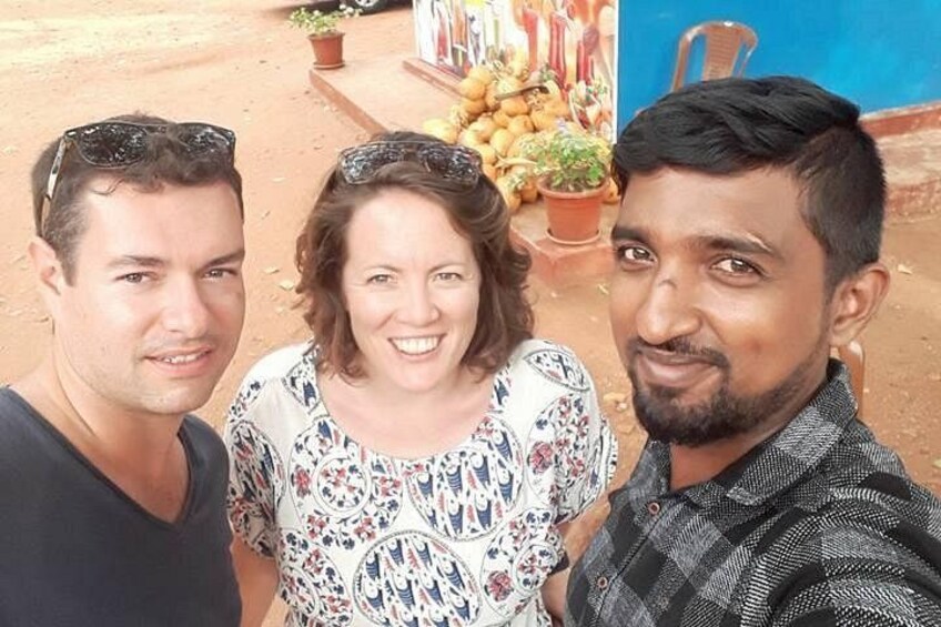Tre personer utomhus, en marknadsstånd med frukt och en blå vägg. 5