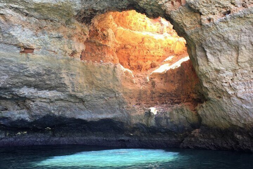 Una cueva con un interior de color naranja brillante y agua azul cristalina en el fondo. 1