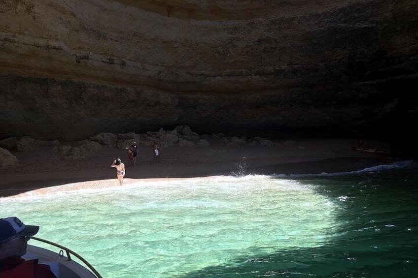 Una playa con agua turquesa cristalina, techo de una cueva rocosa y personas caminando por la orilla. 3