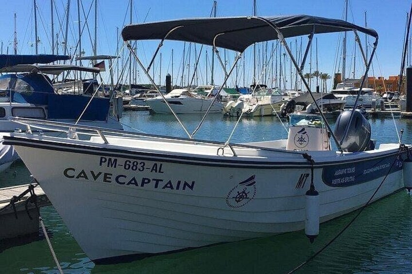 A boat named 'Cave Captain' docked at a marina with other boats. 2