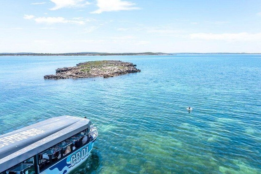 A clear blue sea with a boat named 'GBUL' and a small rocky island in the distance. 3