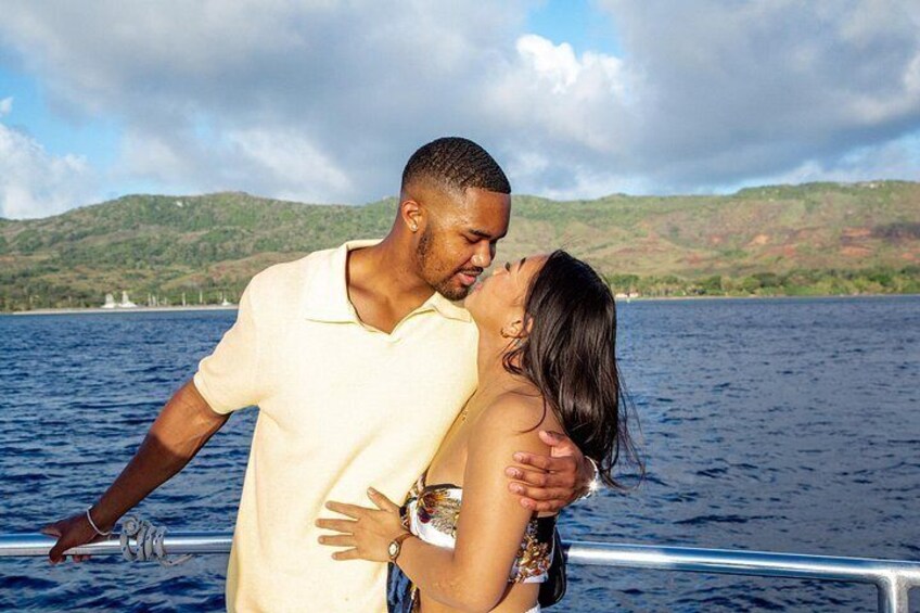 A couple embracing on a boat with a lake and hills in the background. 2