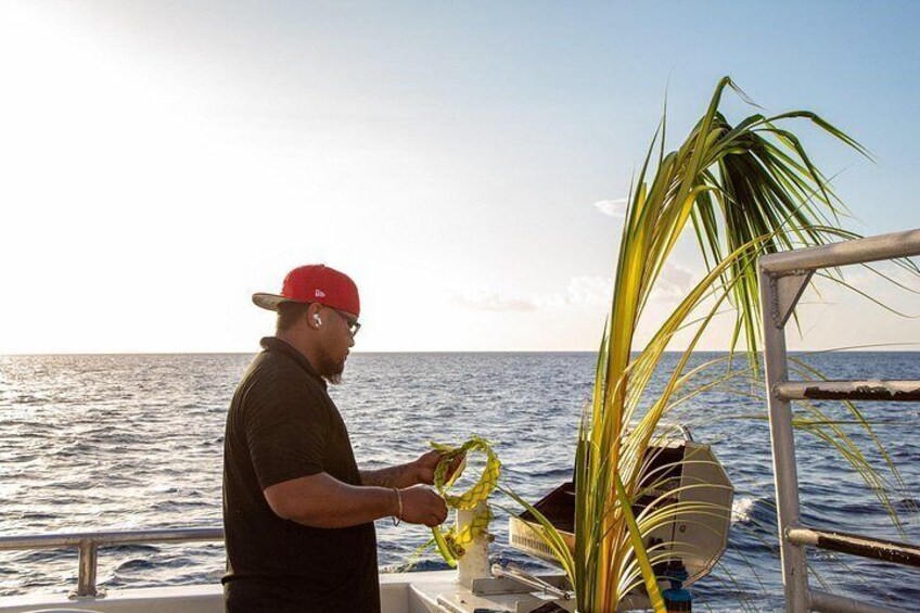 A person on a boat near the ocean, holding a yellow rope, with a palm tree and a metal structure in the background. 3