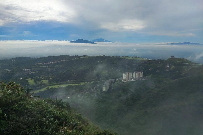 A mountainous landscape with a valley, buildings, and a cloud-covered mountain range. 3