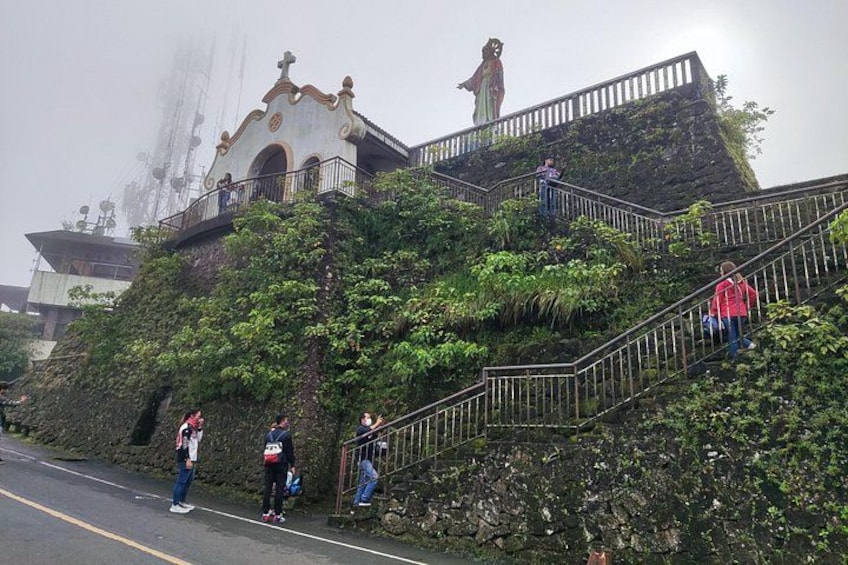A staircase with a statue on top, surrounded by greenery. 2