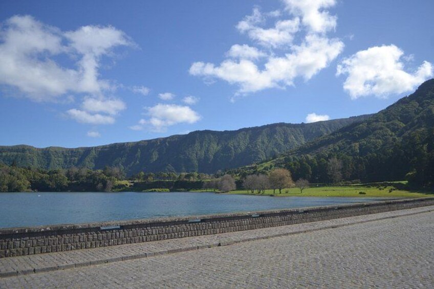 Un lago, un muro de piedra y una montaña boscosa. 3