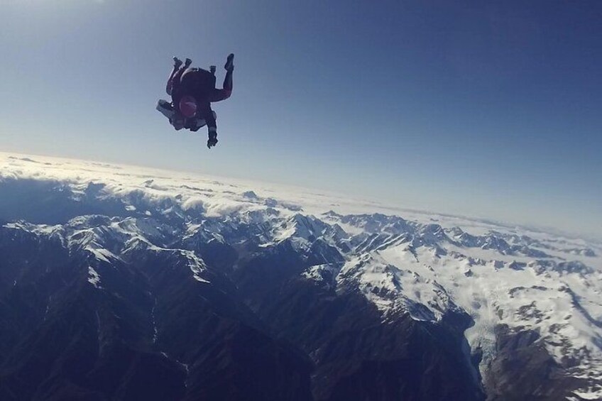 Una persona haciendo paracaidismo sobre montañas nevadas. 5