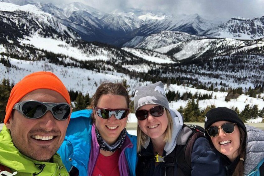 Four people in winter clothing with a mountainous landscape in the background. 5