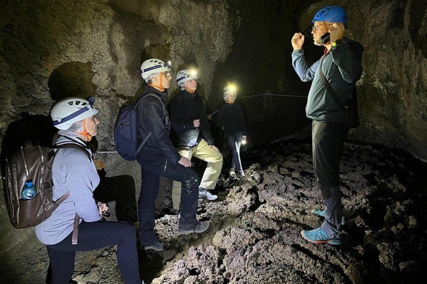 A group of people in a cave with headlamps, wearing helmets and backpacks. 3