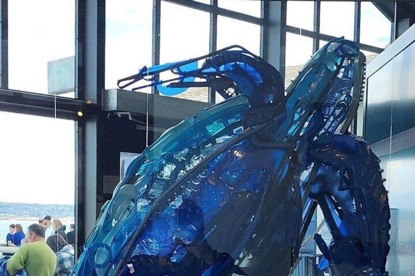 A large glass sculpture of a mechanical structure in an indoor setting. 2