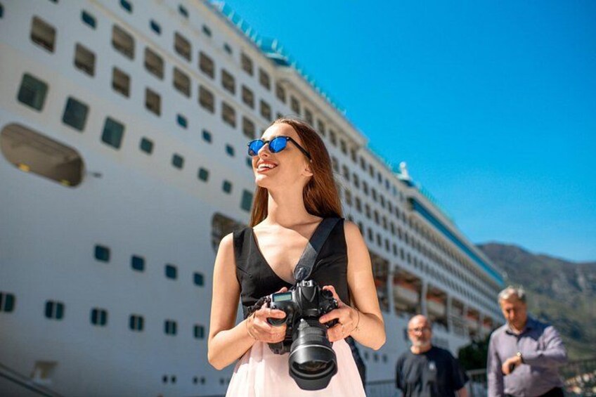 Una persona sosteniendo una cámara, con un gran crucero al fondo. 3
