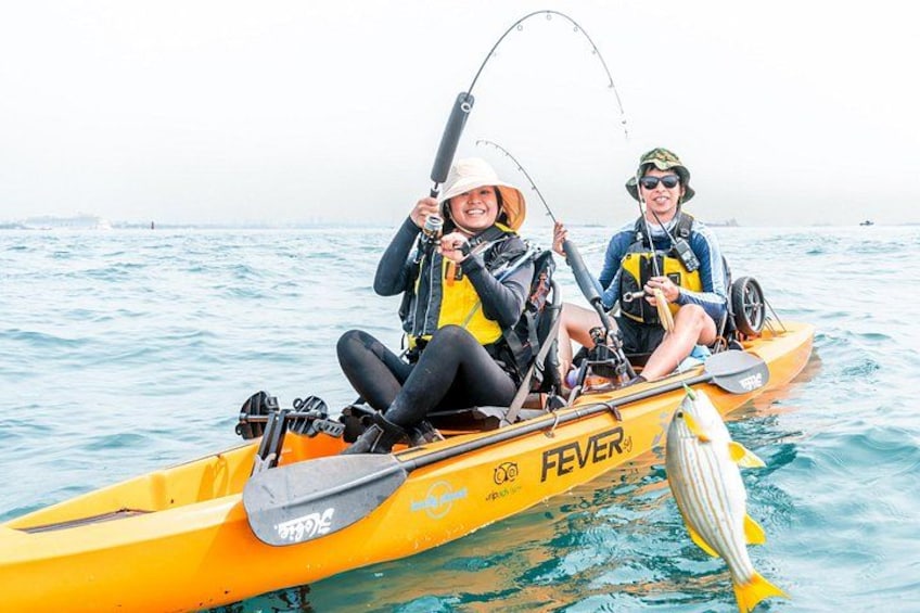 Two people in a yellow kayak on calm water, fishing. 4