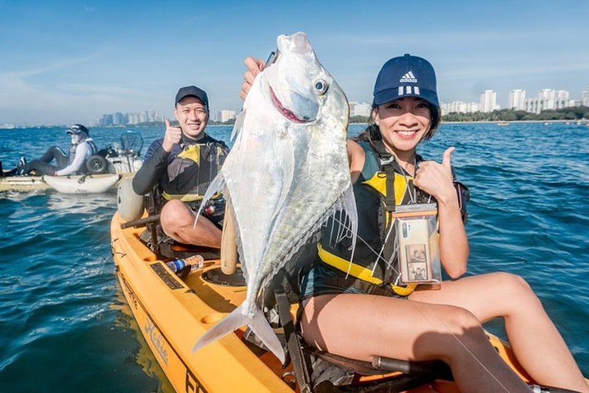 Two people on a yellow boat holding a large fish, with a city skyline in the background. 5