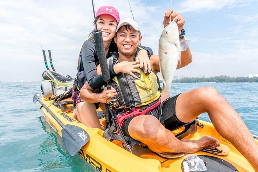 Two people on a yellow kayak holding a fish. 3