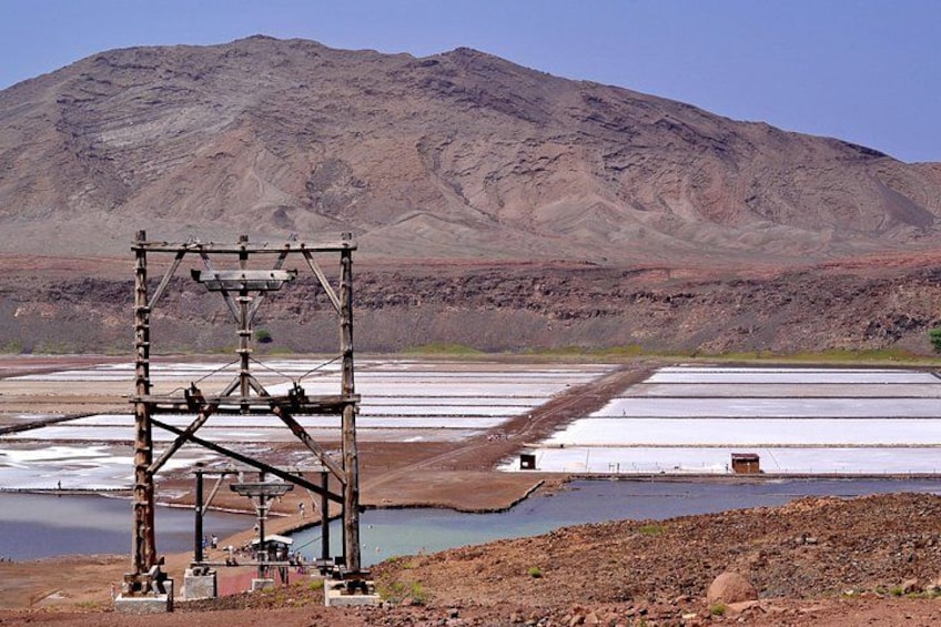 A salt flat with a large salt extraction structure in the foreground and a mountain in the background. 3