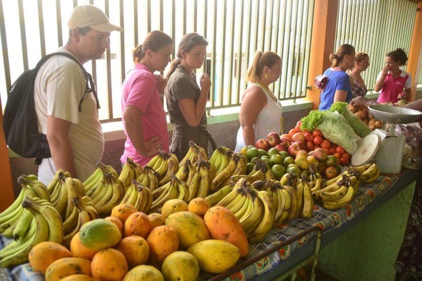 Un mercado de frutas con plátanos, naranjas y otros productos frescos. 4