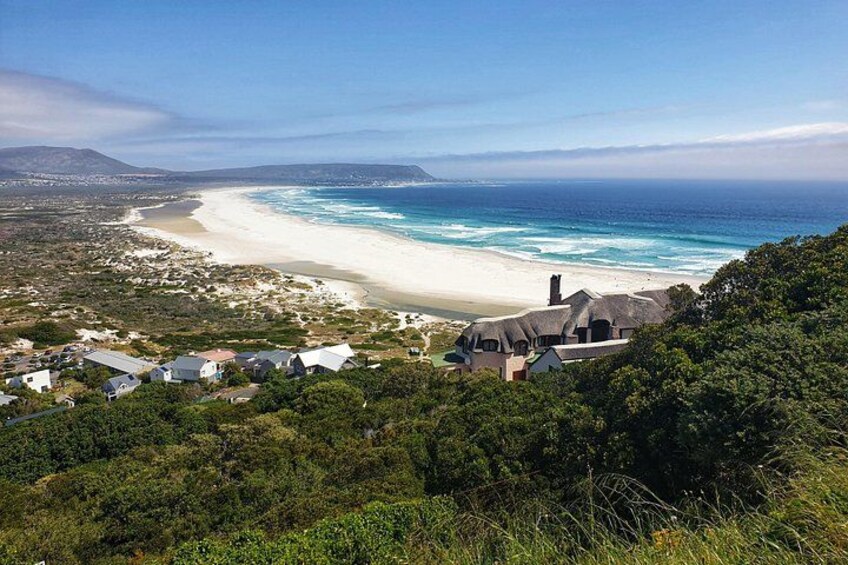 A coastal landscape with a beach, ocean, and houses on a hillside. 2