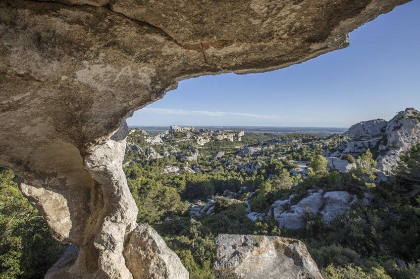 Un paisaje rocoso con una gran formación pétrea en primer plano y una vista de un pueblo a lo lejos. 1