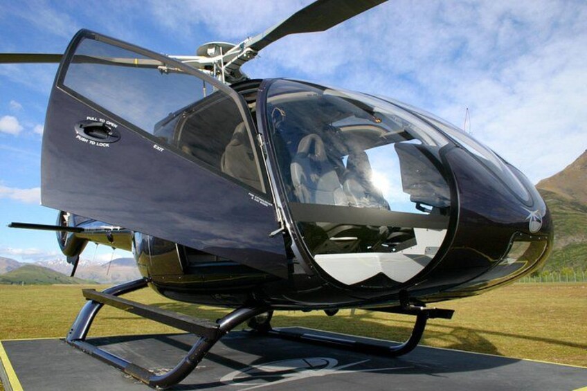 En helikopter parkeret på en startbane med et bjergrigt landskab i baggrunden. 5