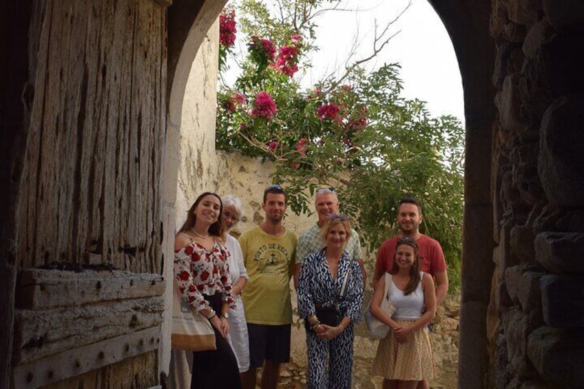 Un grupo de personas de pie en un arco de piedra con un edificio rústico y árboles en flor al fondo. 5