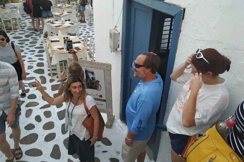 Personas de pie sobre un piso con diseño, algunas tomando fotografías, en un espacio al aire libre con mesas y sillas. 4