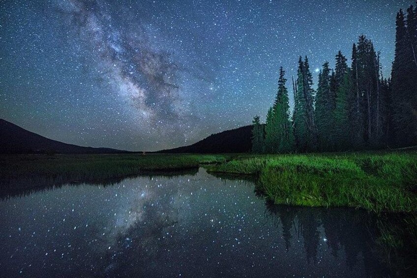 Un ciel étoilé au-dessus d’un lac paisible, avec une forêt en arrière-plan. 2