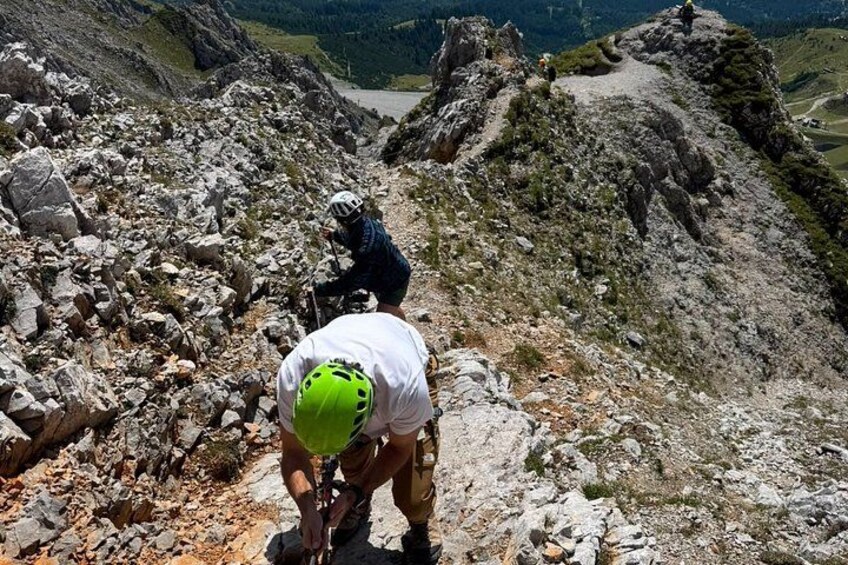 A hiker in a white shirt and green helmet on a rocky mountain trail. 3
