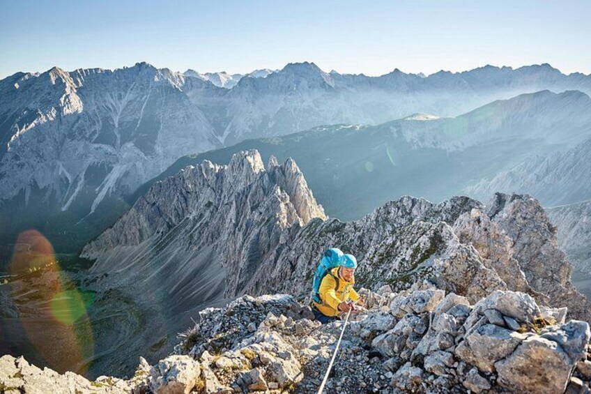 Ein Wanderer auf einem felsigen Berggipfel mit Blick auf ferne Berge. 2