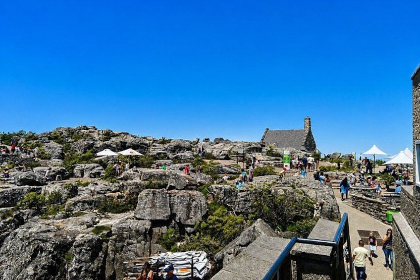A rocky landscape with a stone building and people walking on a path. 2