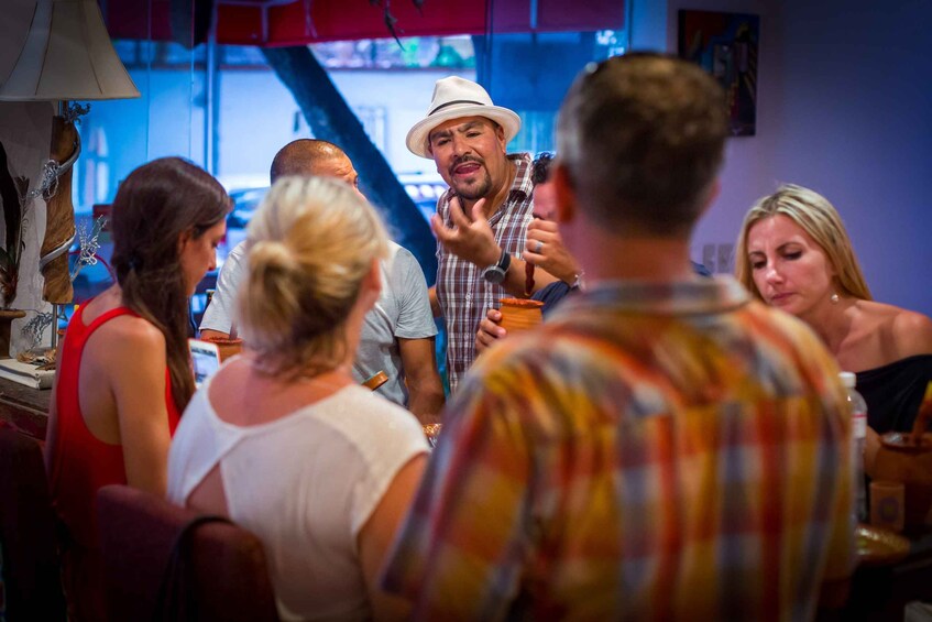 A group of people in a social setting, possibly a bar or restaurant, with a person speaking to the group. 2