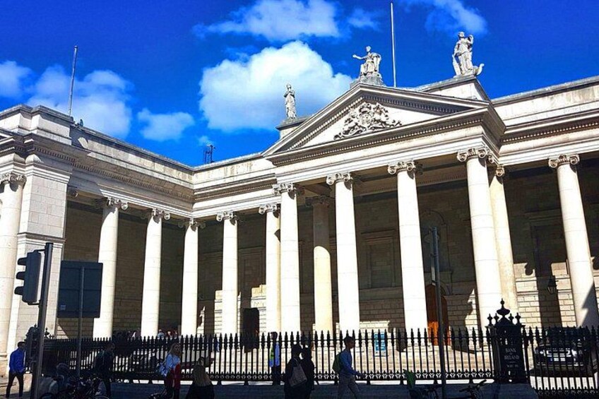 Un edificio neoclásico con columnas y estatuas, bajo un cielo azul despejado. 4