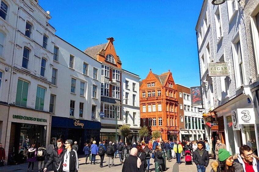 Una calle concurrida con peatones, edificios históricos y comercios. 3
