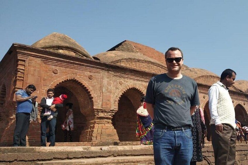 A man standing in front of a brick building with arches and domes. 3