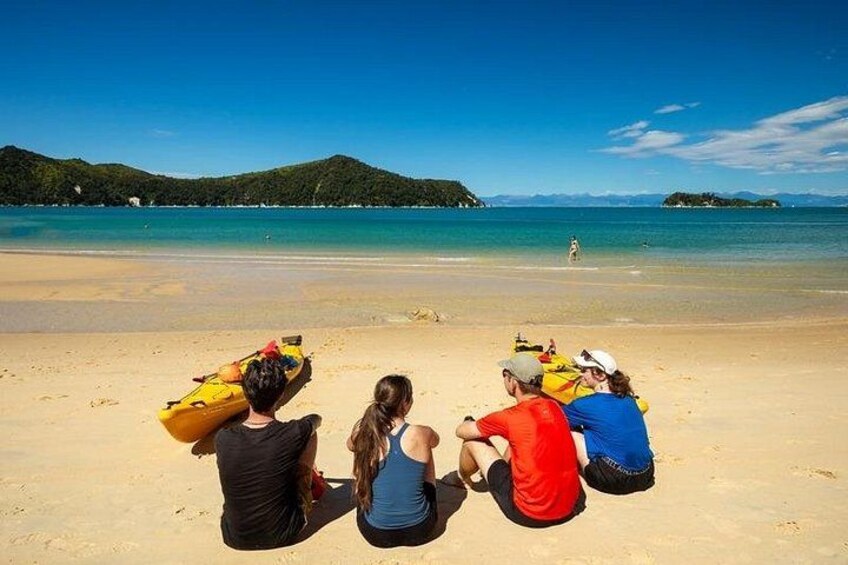 A beach with people sitting and kayaks. 2